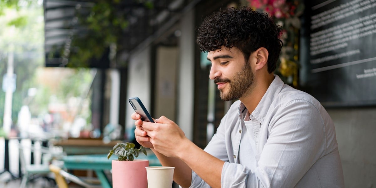 hombre sentando usando celular