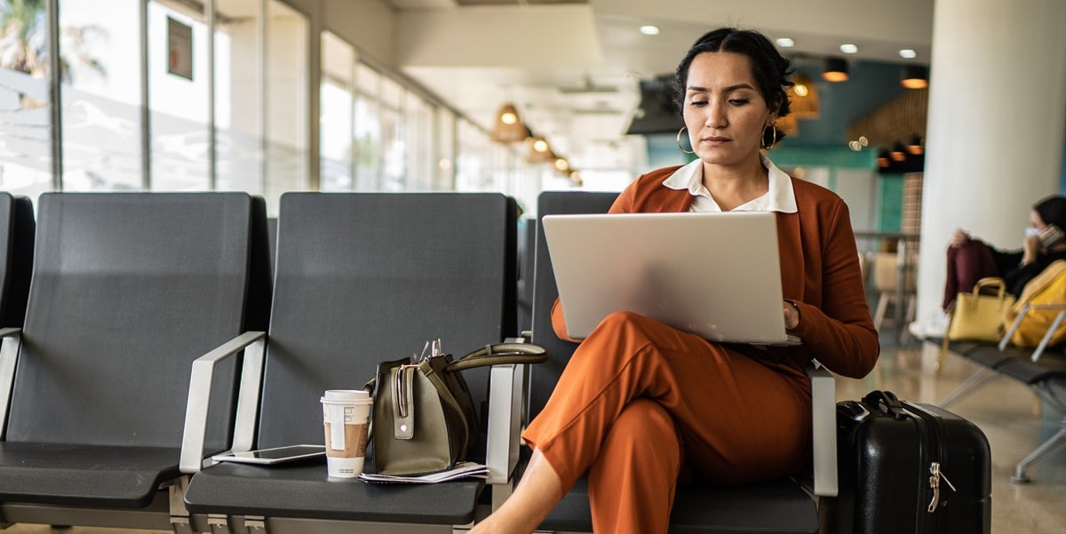 business traveler sitting in an airport lounge, working on laptop