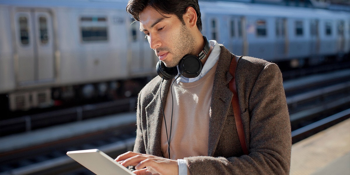 man_with_tablet_and_headphones_in_trainstation