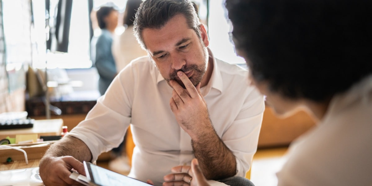 mature man looking at a tablet that a colleague is showing him