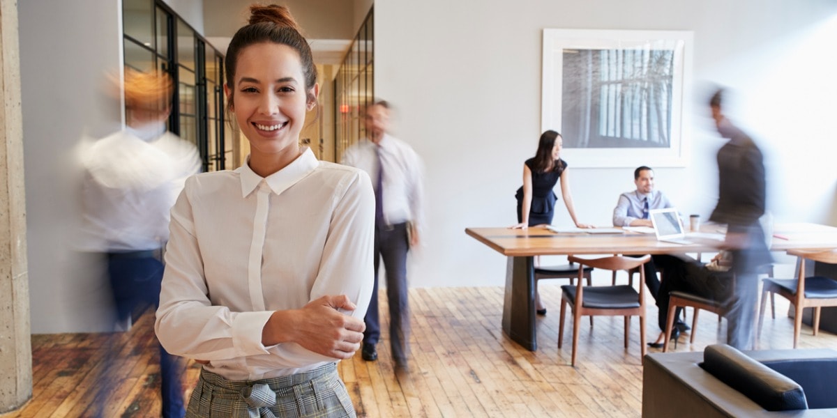 smiling young woman in an office with her arms folded