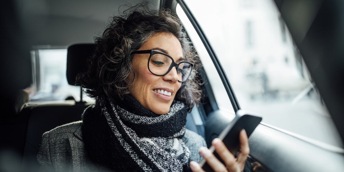 mujer en carro con celular en mano