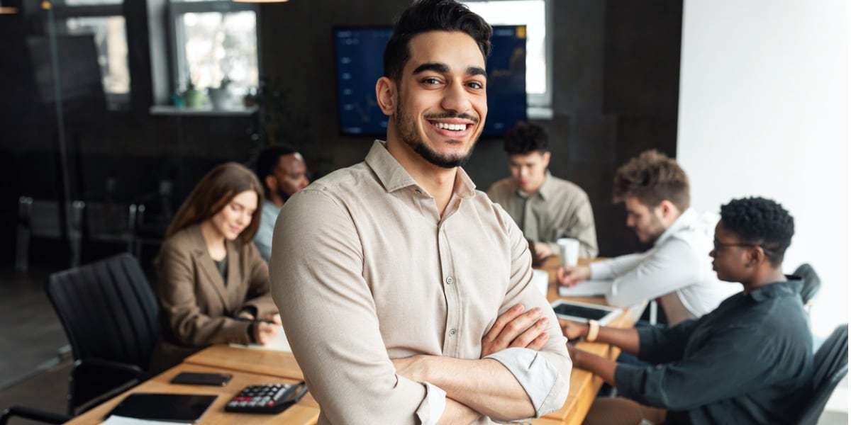 photo of young businessman smiling with meeting behind him