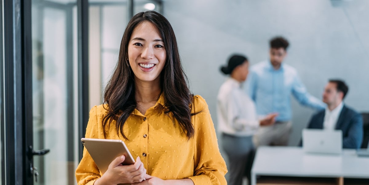 woman in the office smiling holding a tablet