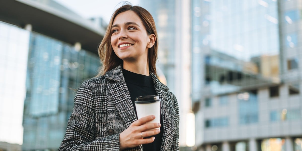 woman standing outside, holding coffee cup