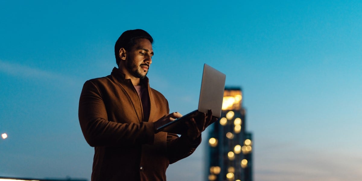 professional man standing outside, holding laptop