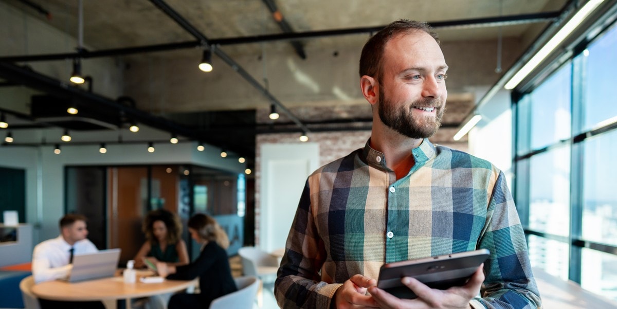 professional man smiling, in the office, holding tablet