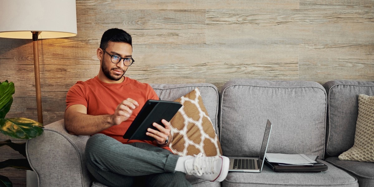 man sitting on a couch using a tablet