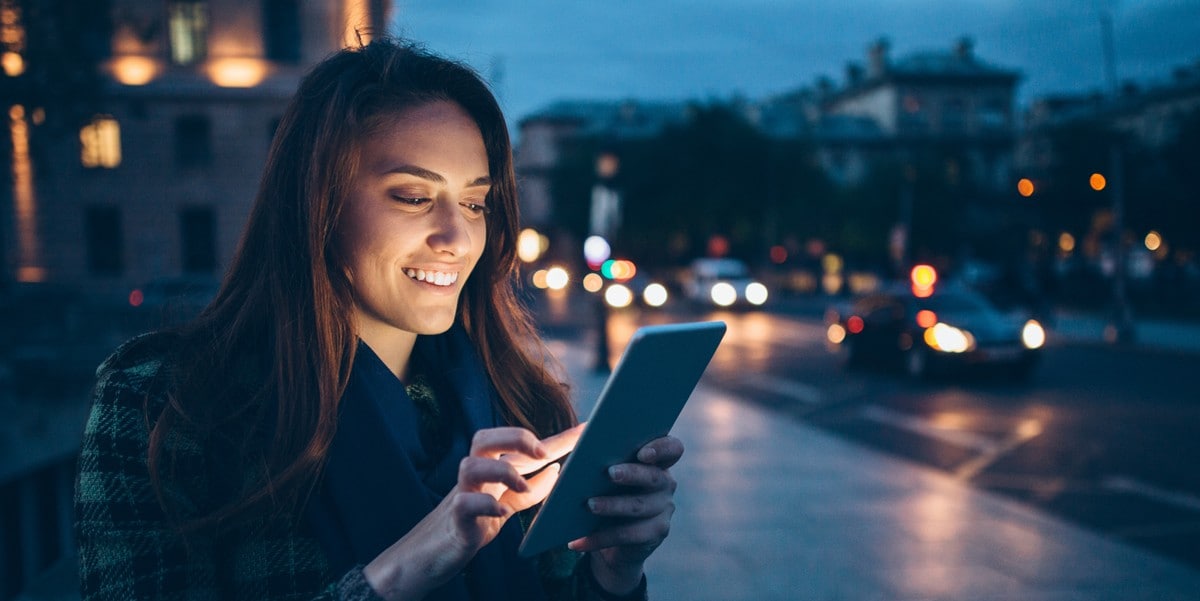 woman traveler using phone outside at night in city