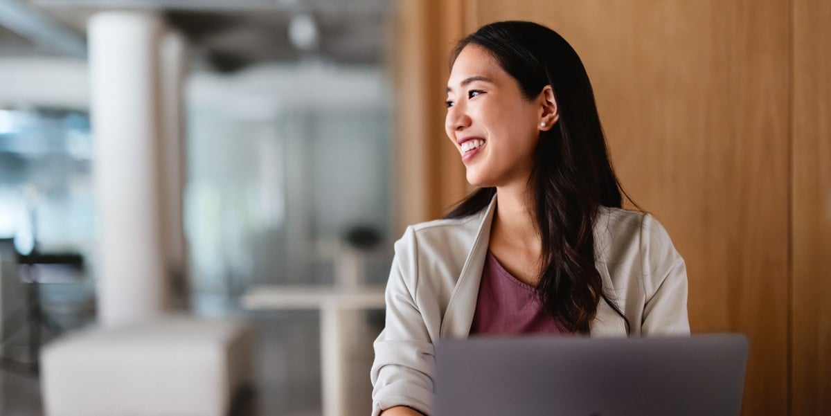 mujer profesional sonriendo, en la oficina con laptop