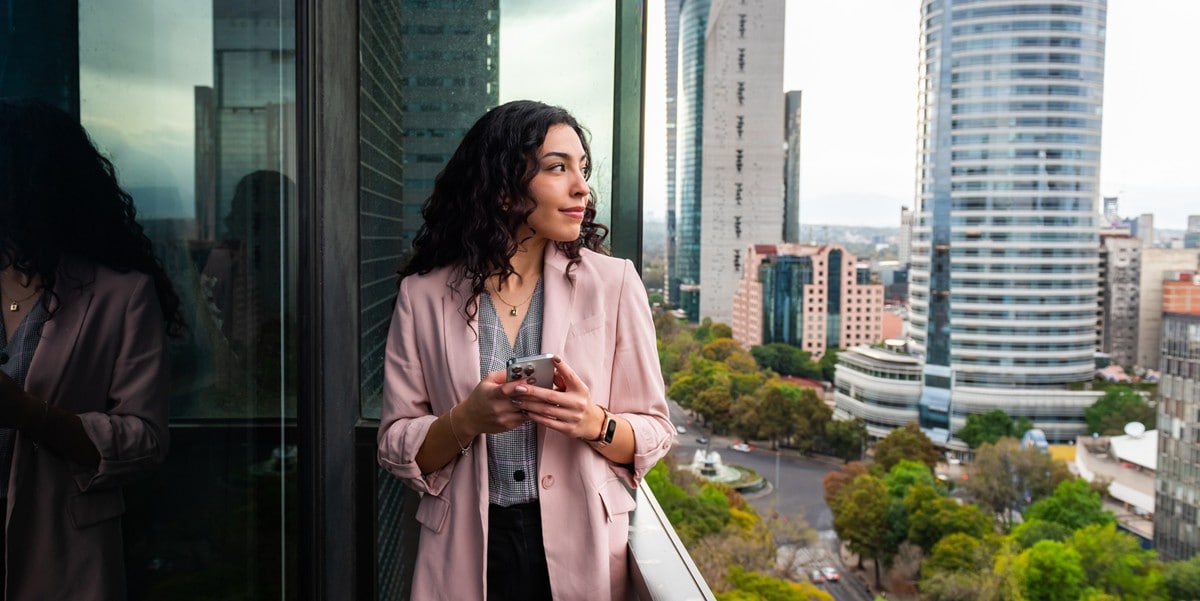 woman standing on balcony holding cellphone